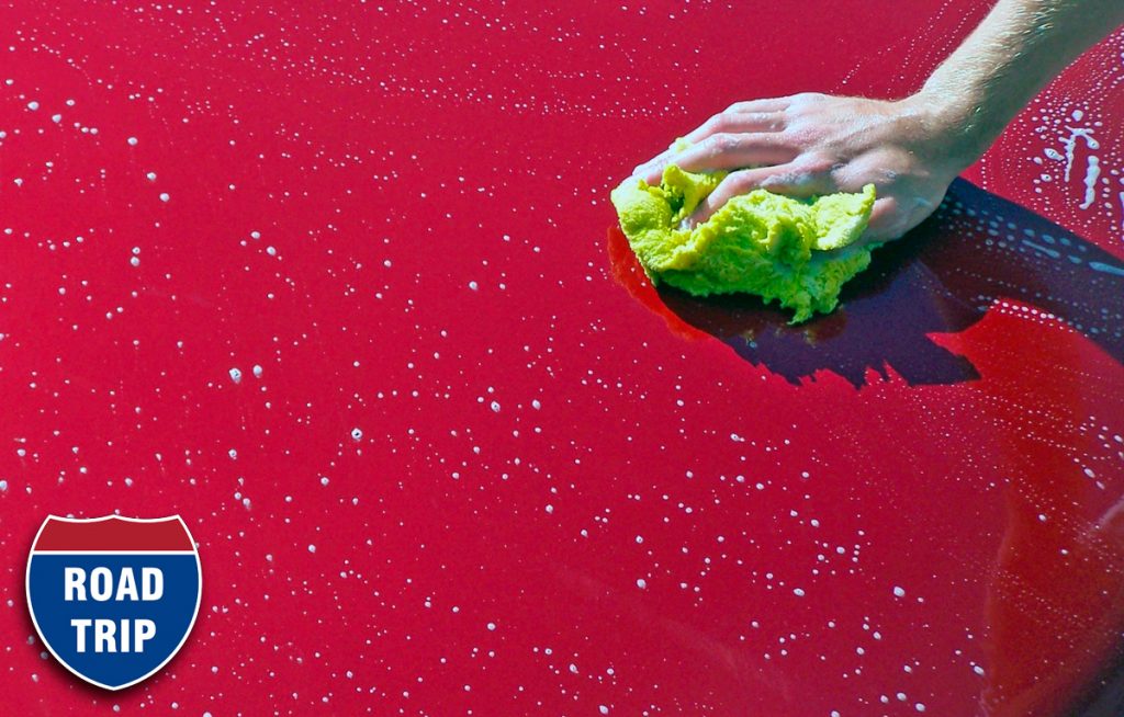 Person washing red car hood